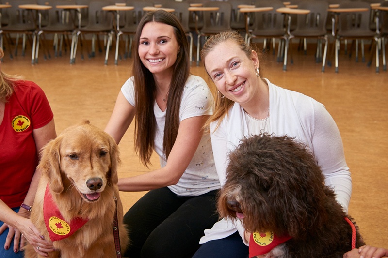 Two female students with Therapy dogs from PAWS Canada