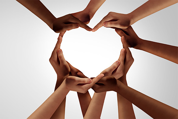 A gathering of hands of different skin tones that form the shape of a heart